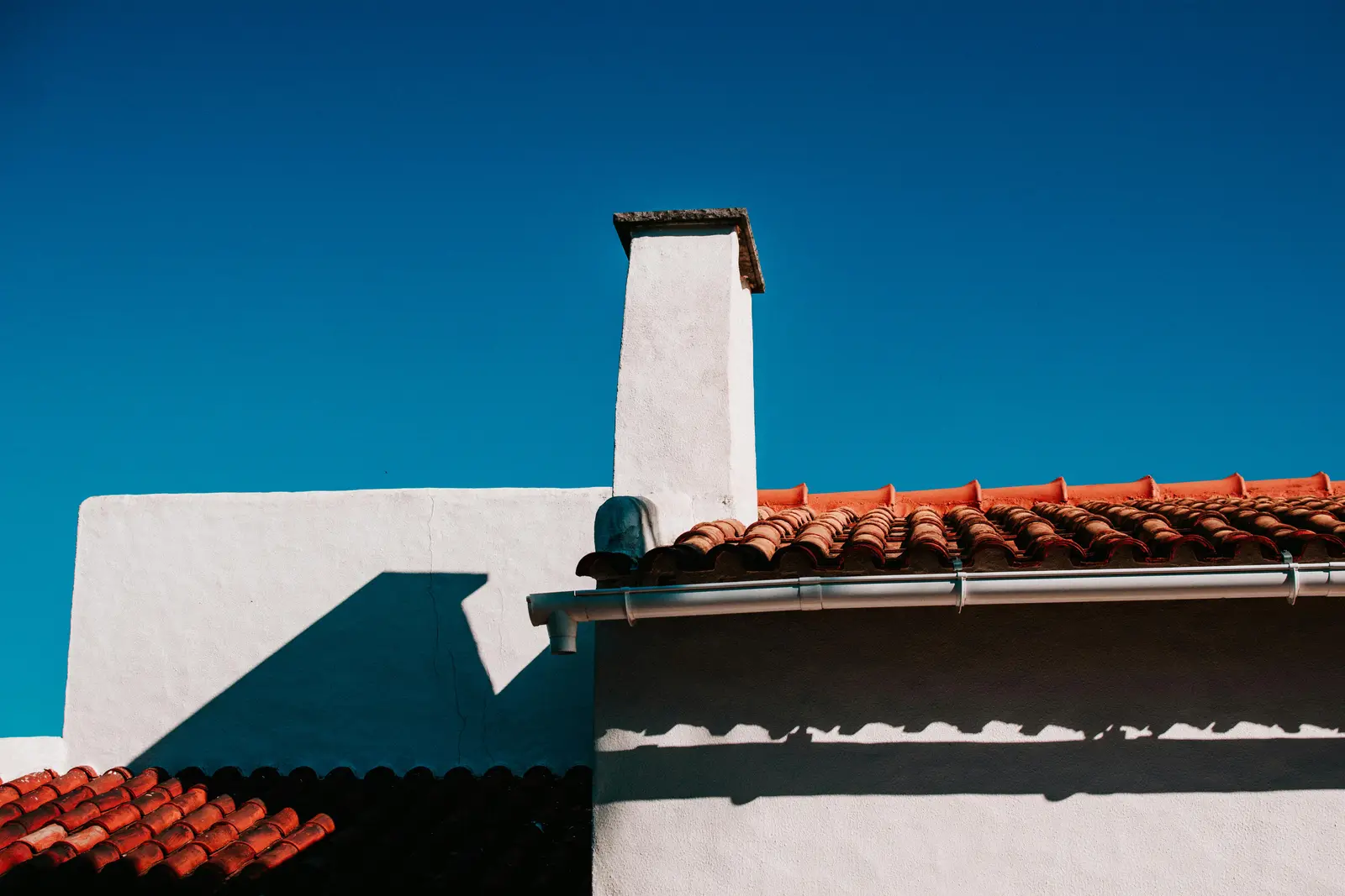 Gutter and downpipe on a rendered home under a tiled roof